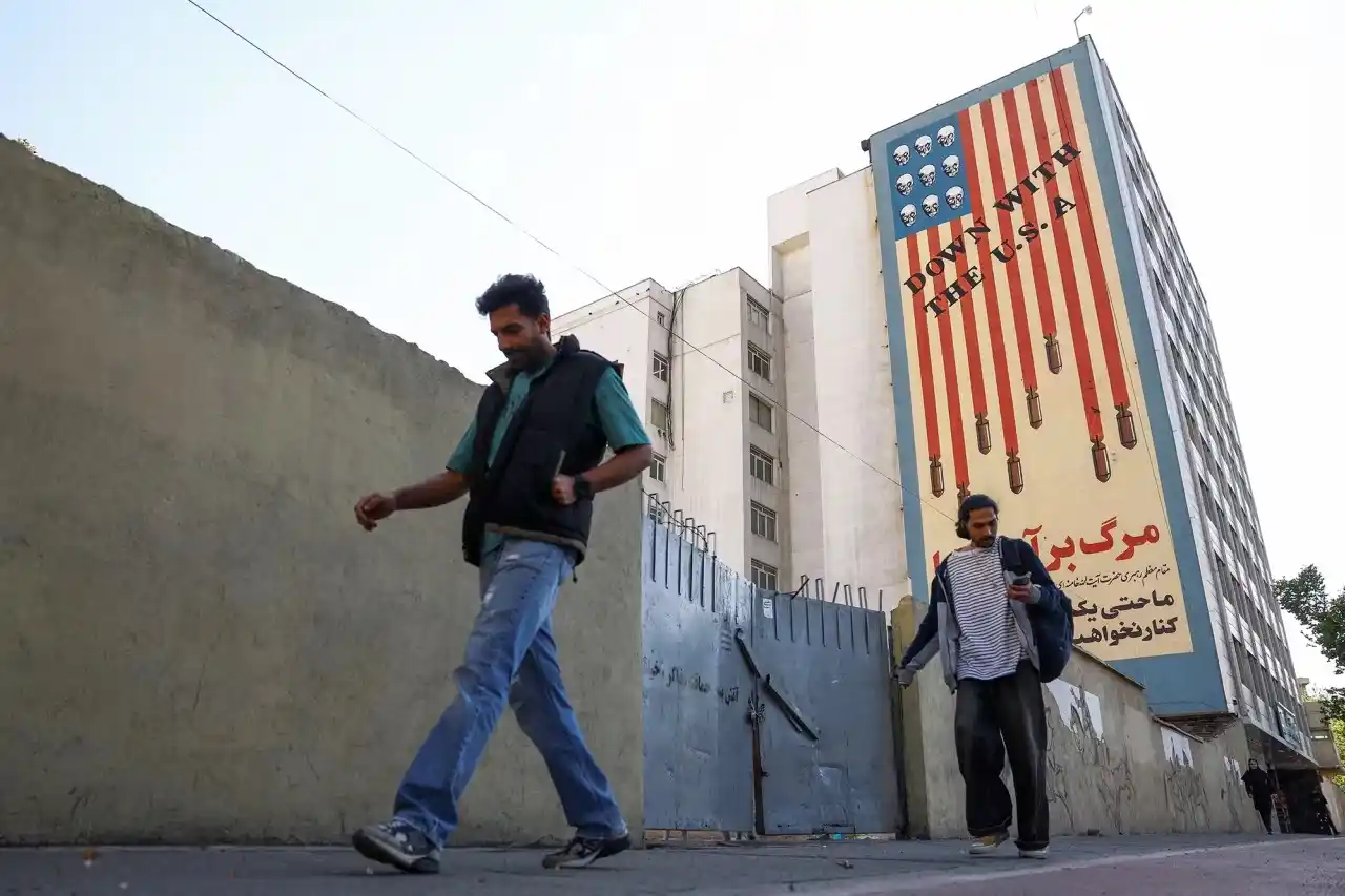 People walk past an anti-U.S. mural on a building in Tehran.
