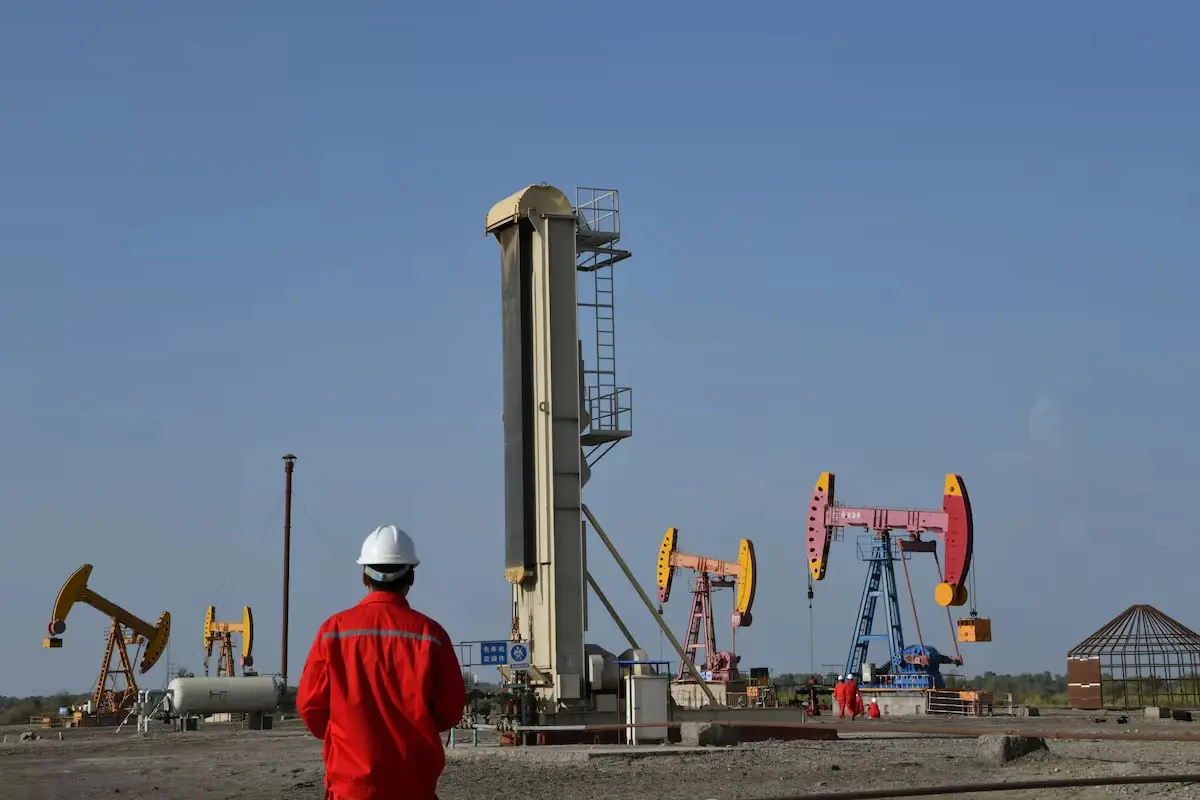 Workers are seen near pumpjacks at a China National Petroleum Corp (CNPC) oil field in Bayingol, Xinjiang Uighur Autonomous Region, China 