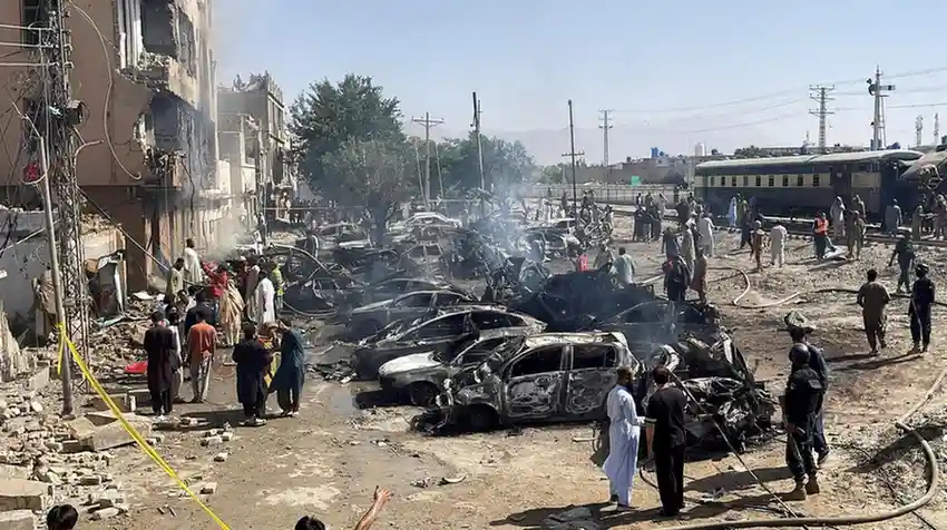 People and police officers gather after a blast near a railway track in Quetta, Pakistan