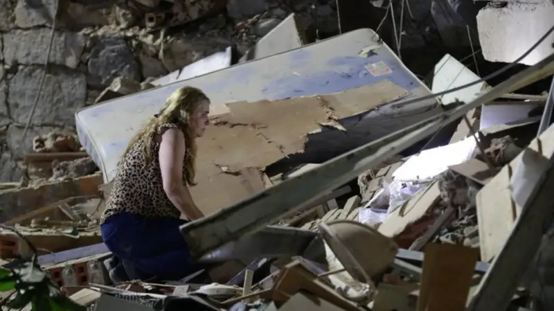 A woman kneels on a pile of rubble from a collapsed building in Caracas.