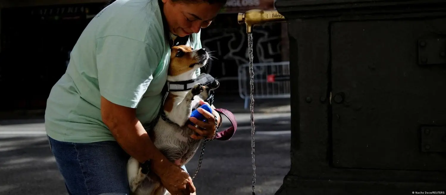 A woman giving water to her dog.