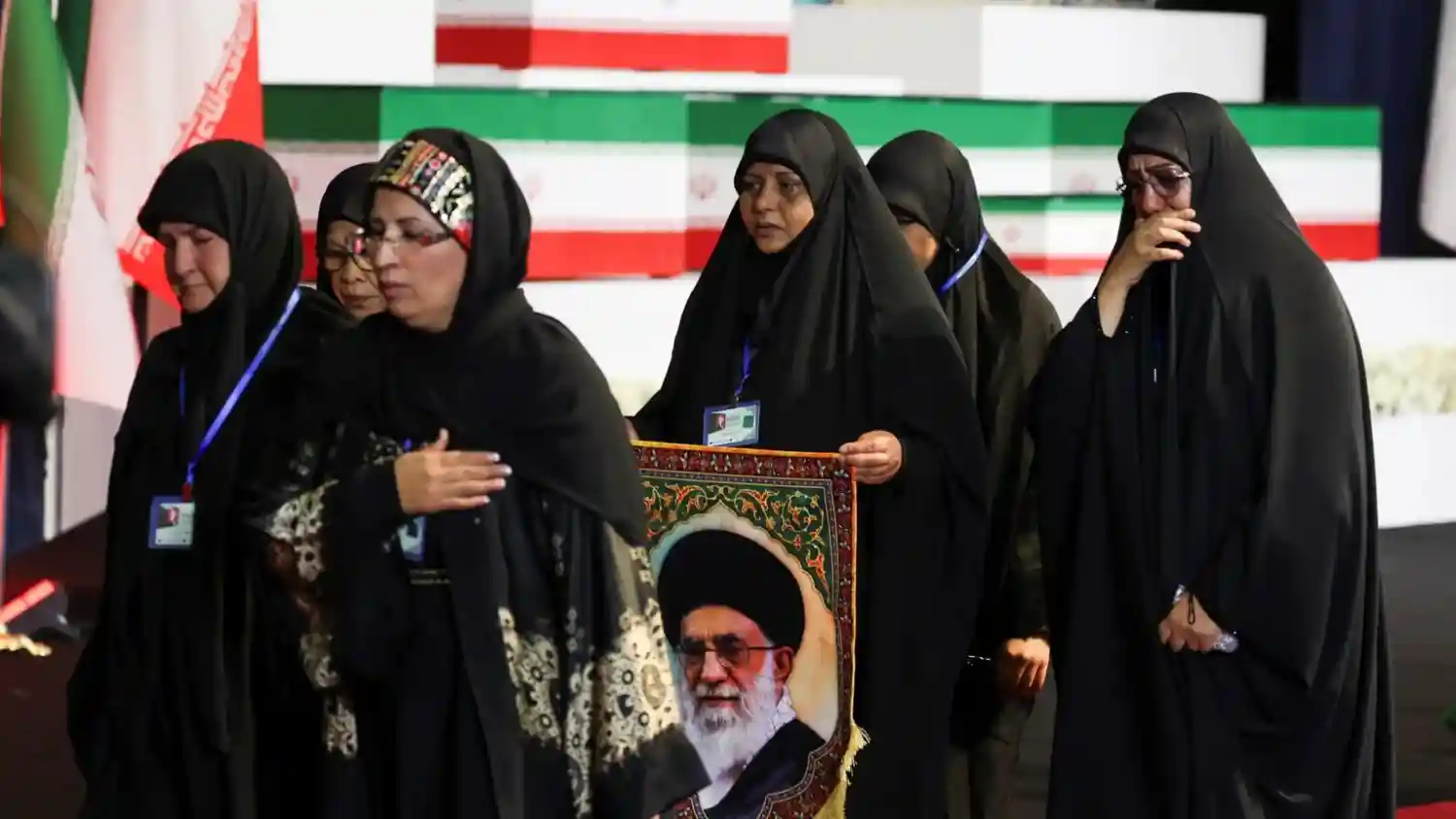 Some Iranian women are crying while holding posters of Khamenei.