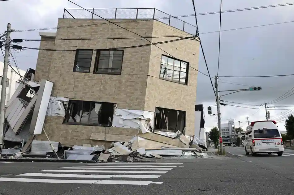 An ambulance passes by a collapsed building in Yatsushiro, Kumamoto prefecture, on Wednesday.