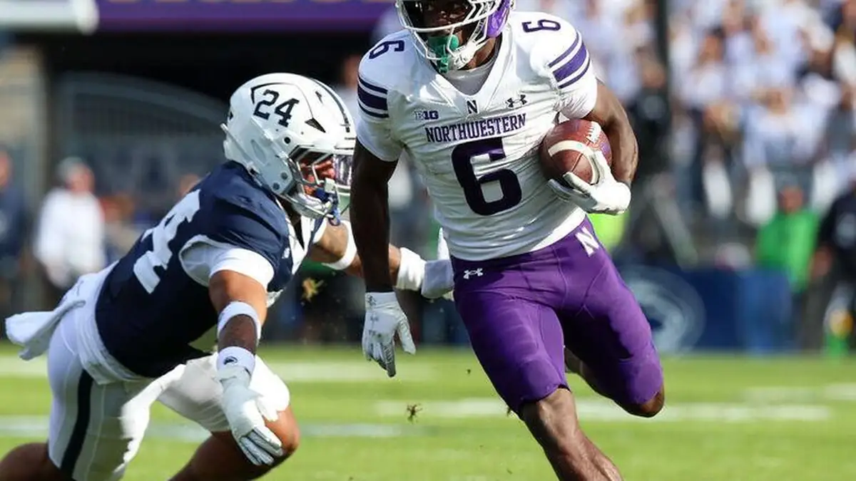 Northwestern running back carries the football while evading a Penn State defender during a Big Ten game