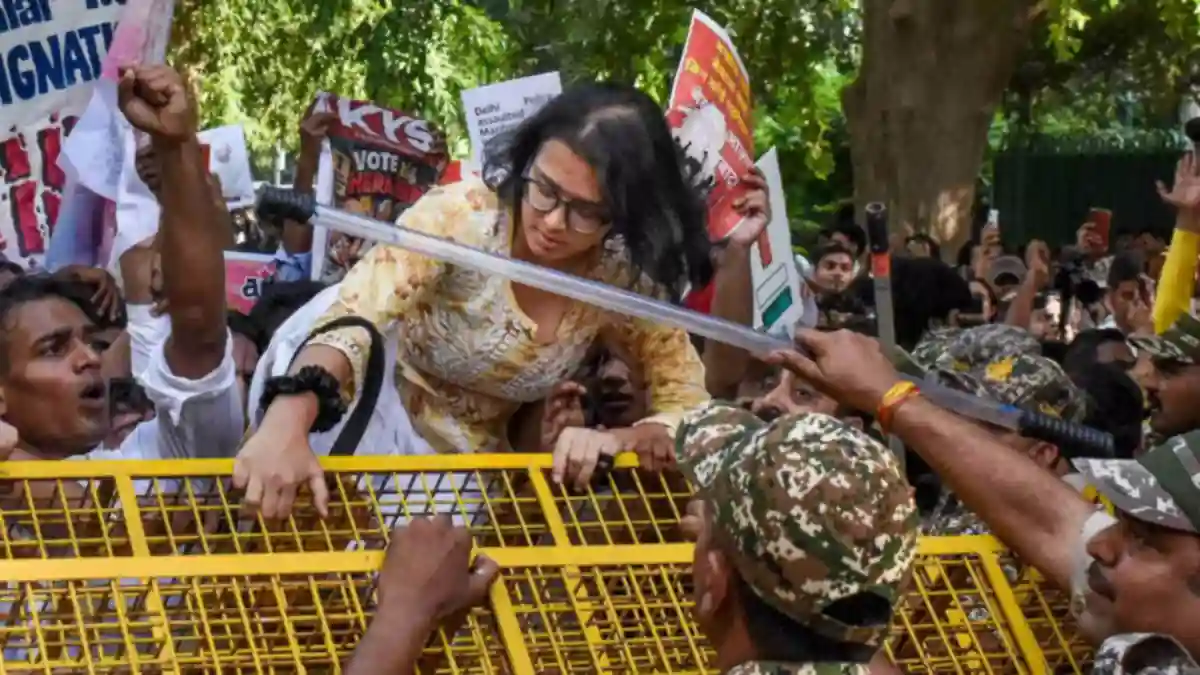 AISA national president Neha Bora climbs a police barricade near Ashoka Road as student activists attempt to march towards Jantar Mantar, demanding the removal of CEC Gyanesh Kumar in New Delhi on Sunday (October 4). 
