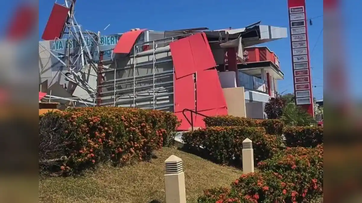 Earthquake-damaged commercial building in Panama with collapsed exterior panels, exposed structural elements, and a damaged facade.
