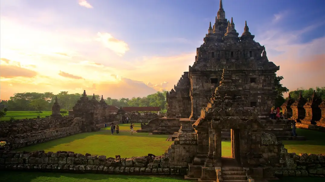 A temple complex with intricate architecture and a lush green lawn.