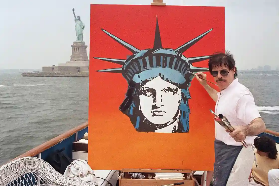 Peter Max works on a painting of the Statue of Liberty aboard a boat in New York Harbor, on July 4, 1987. 